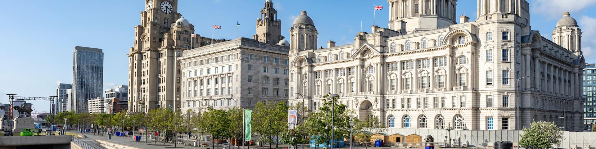 A historic building with multiple domes and towers, surrounded by modern skyscrapers and a clear blue sky.