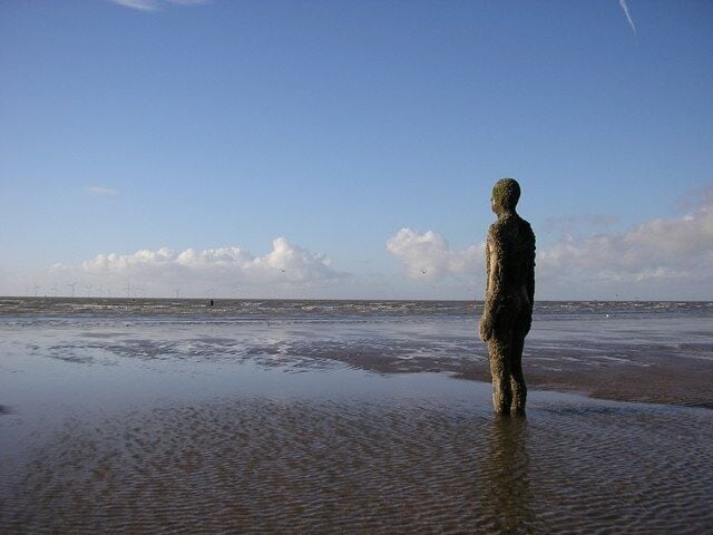 A statue on a beach with the ocean in the background.