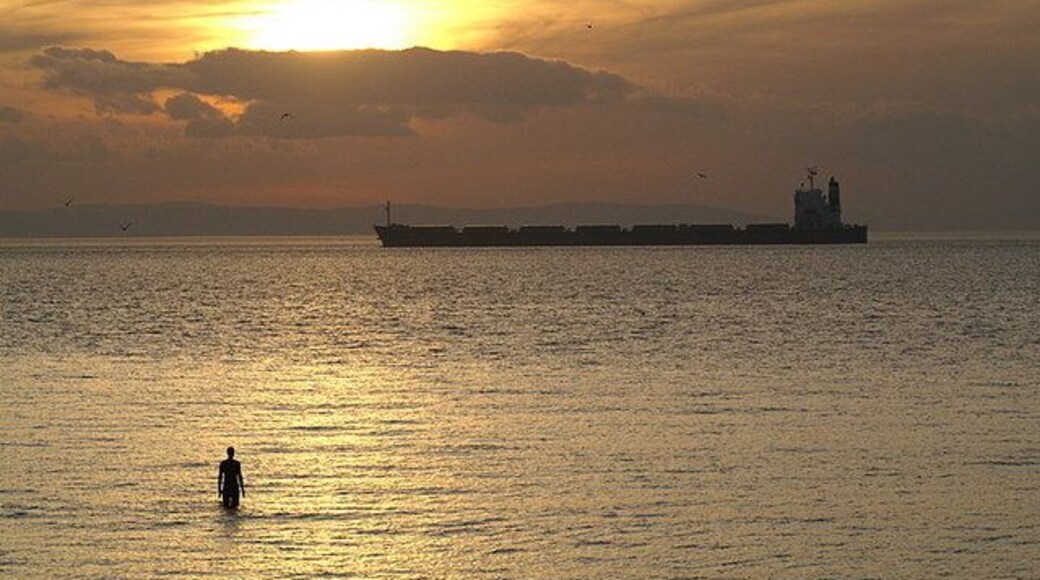 Hall Road at high tide High tide co-incides with sunset, as a bulk carrier enters the Port of Liverpool. One of the landward statues from the Another Place installation is still exposed.