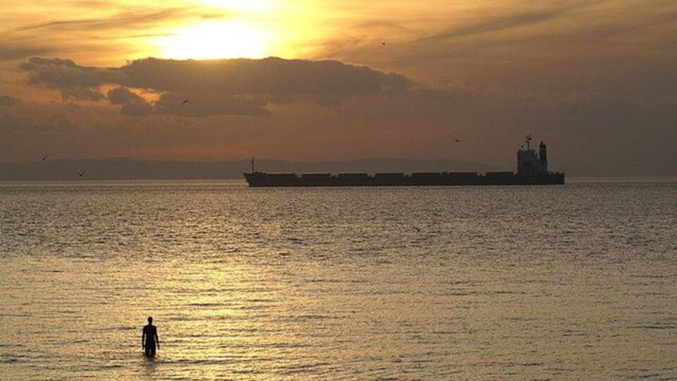 Hall Road at high tide High tide co-incides with sunset, as a bulk carrier enters the Port of Liverpool. One of the landward statues from the Another Place installation is still exposed.