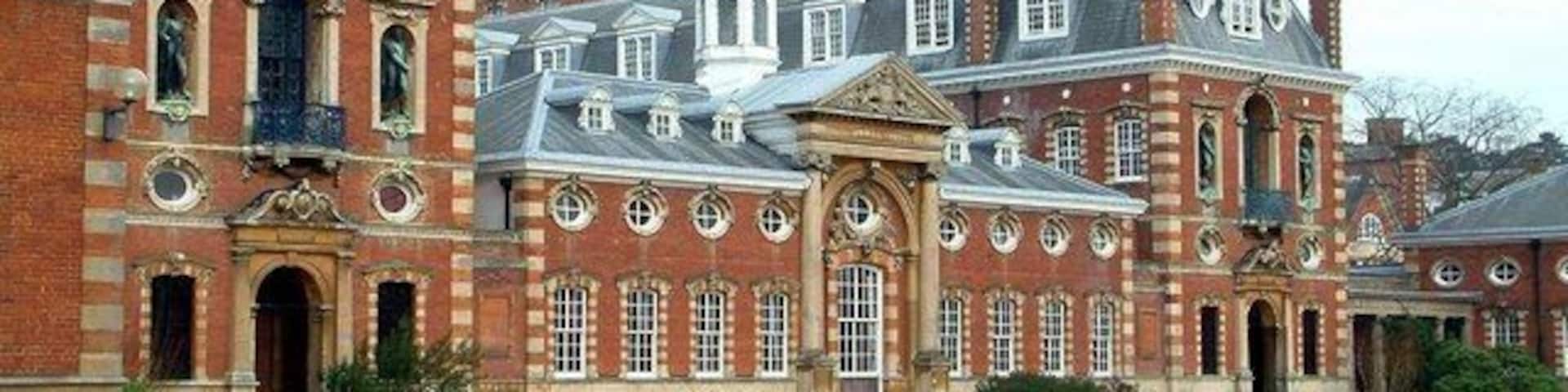 A large, historic brick building with multiple chimneys and a central dome.