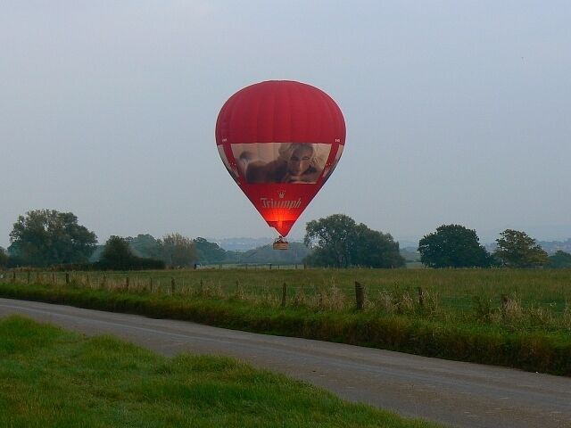 Hot air balloon, Hook, Wiltshire (1). A hot air balloon is about to land on a farm west of Swindon. The gas is being flared to maintain enough buoyancy to permit a soft landing. Time now 17.19 hours. Next image: 579465. Balloon registration G-KNIX.