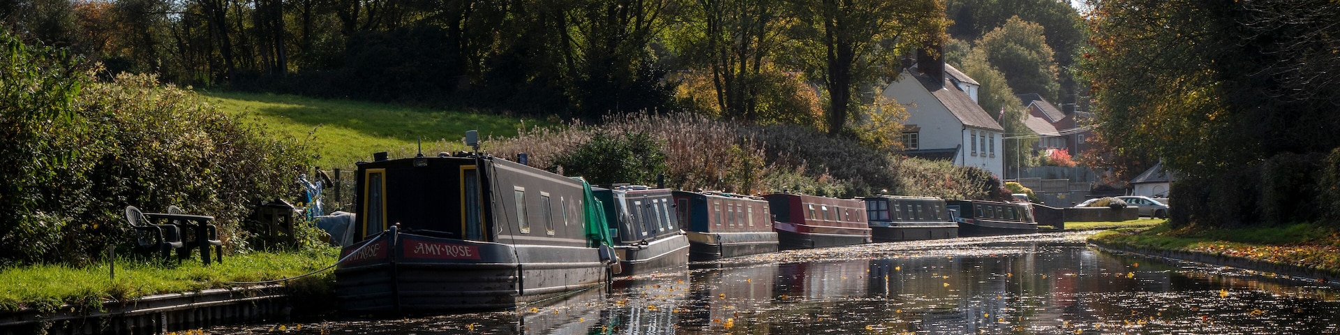 a row of narrow boats on one of Dudley's many canals (or the cut as we know it) near the Stewponey in Stourton. with autumn colours in the trees and still reflective water bellow