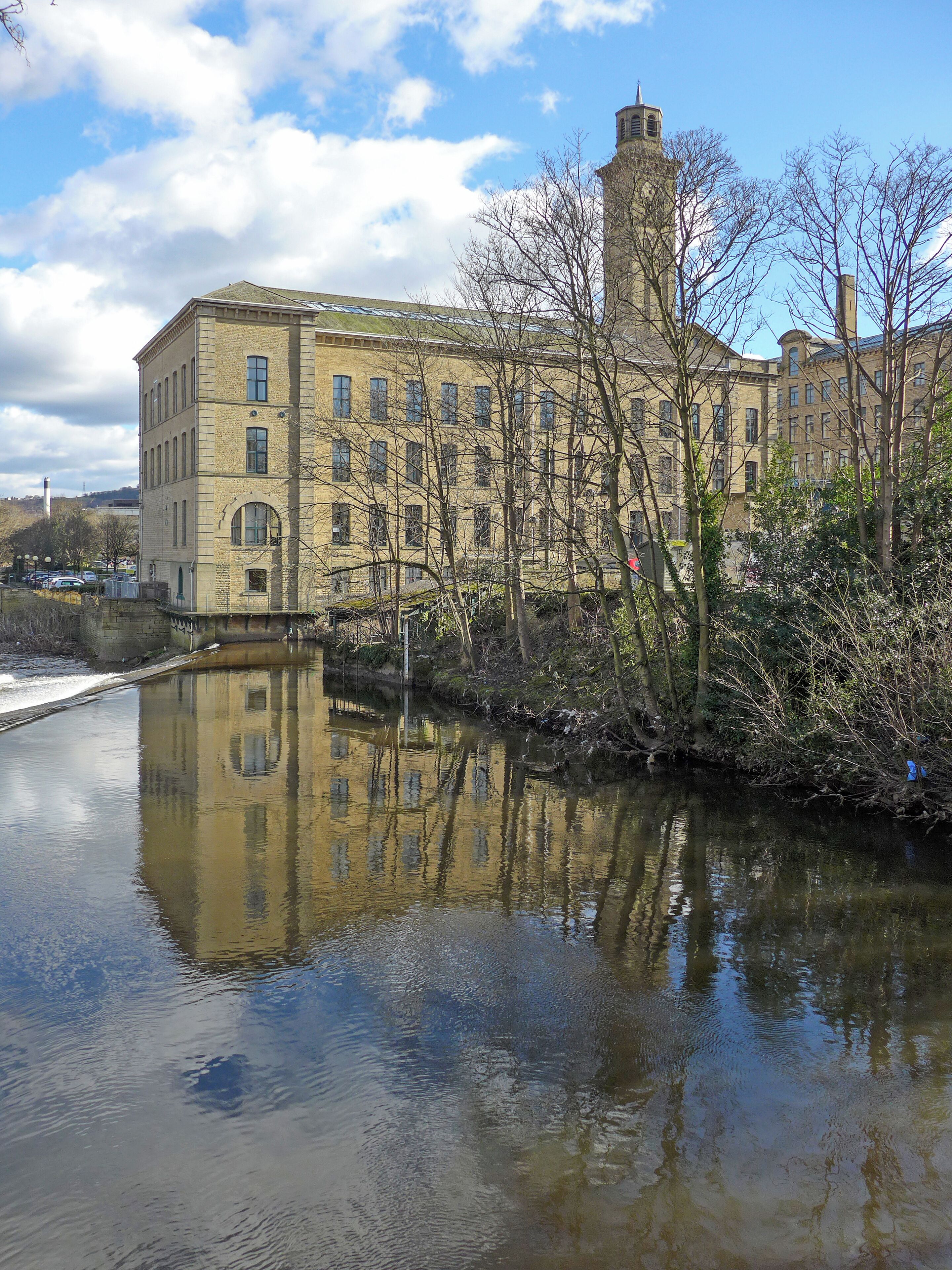 A historic building with a river in front, reflecting the structure.