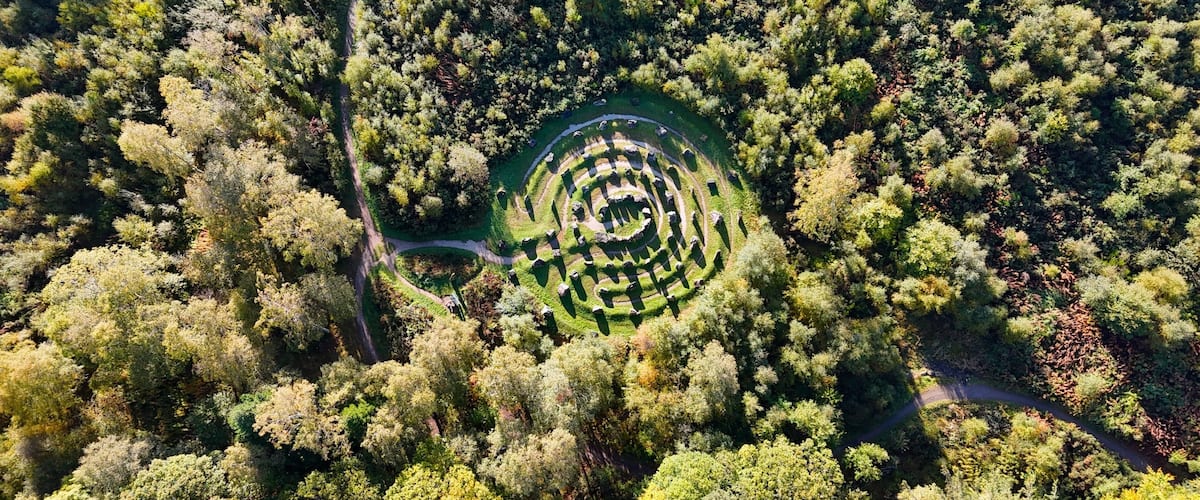 An aerial view of a labyrinth garden surrounded by dense forest.