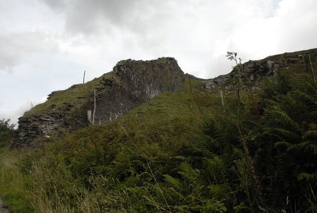 Una montaña escarpada con vegetación verde exuberante y un cielo nublado.