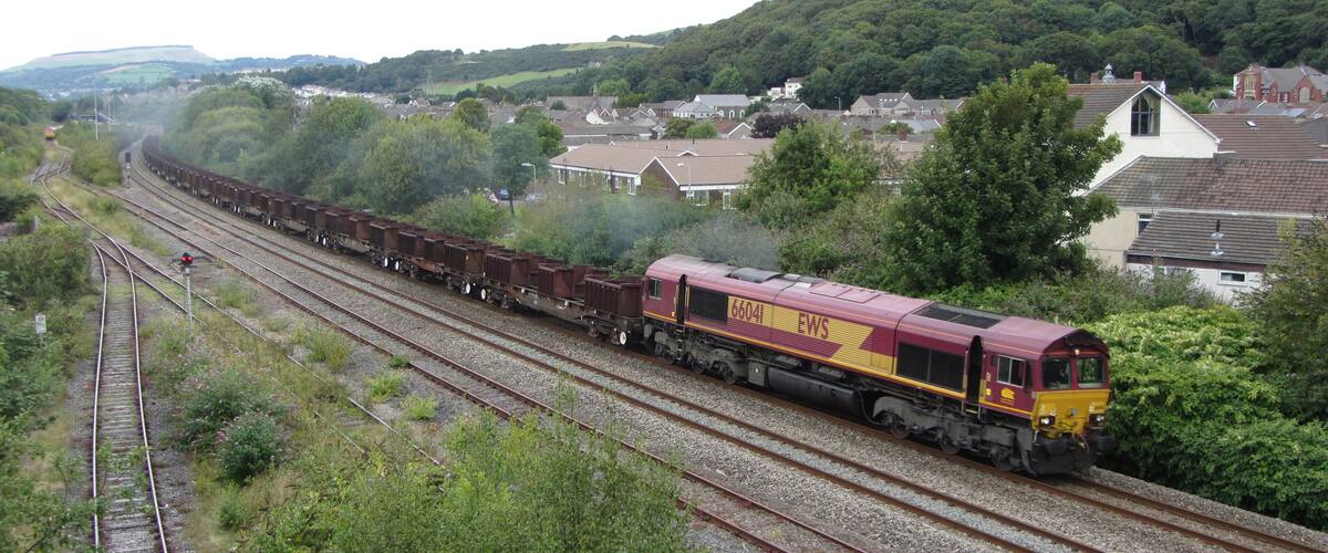 A train on tracks with a forested hillside in the background.