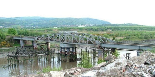 A bridge over a river with a hilly landscape in the background.