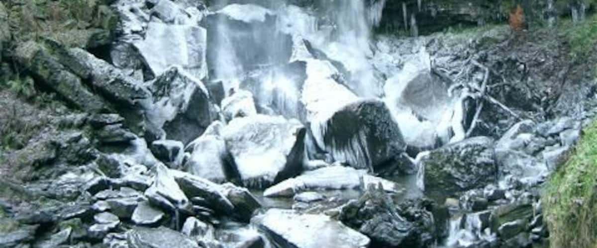 Una cascada fluye sobre rocas en un área boscosa.