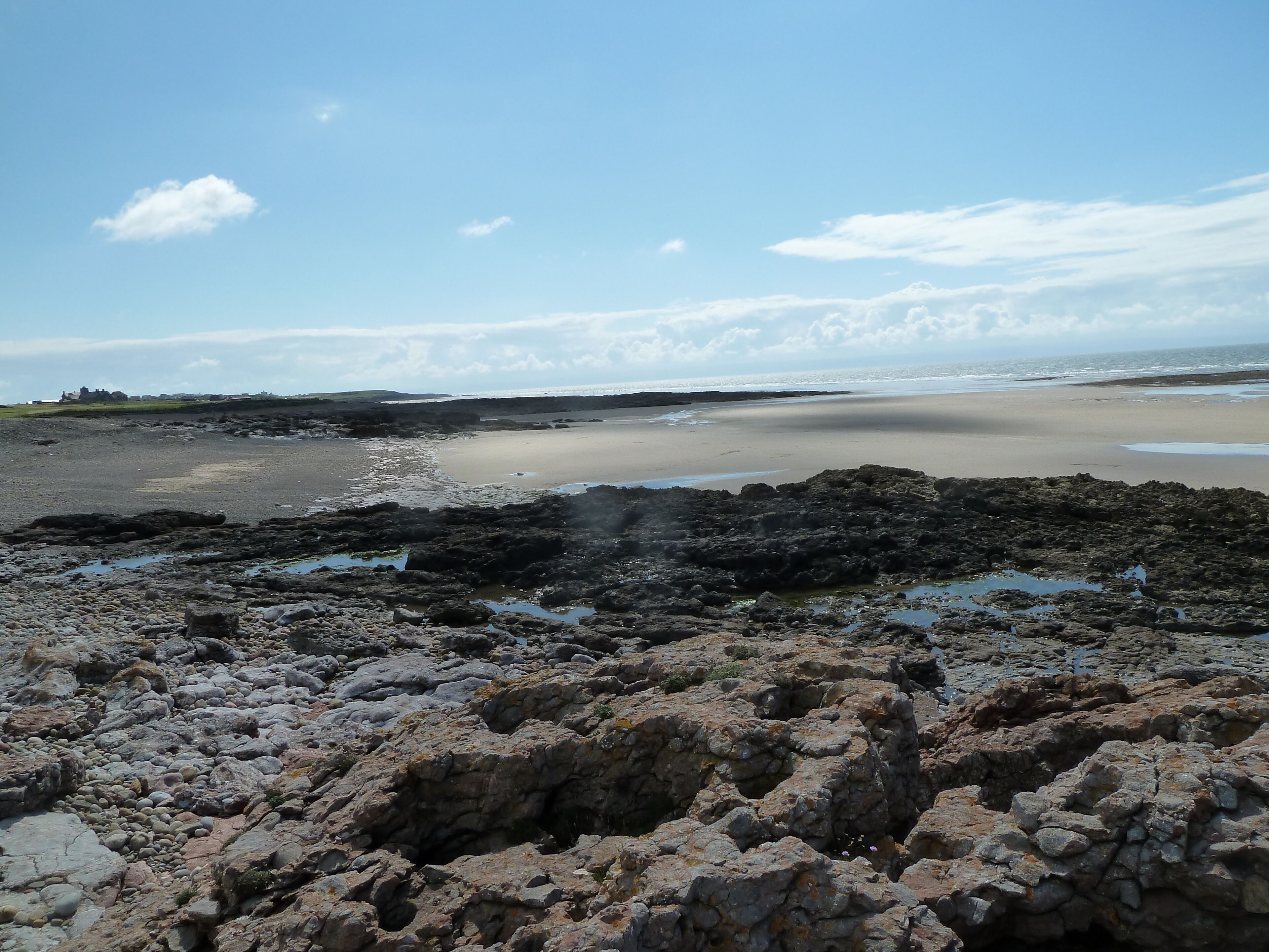A rocky shoreline with a sandy beach and calm sea.