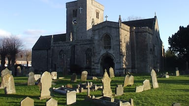 A historic church with a clock tower and a cemetery in front.