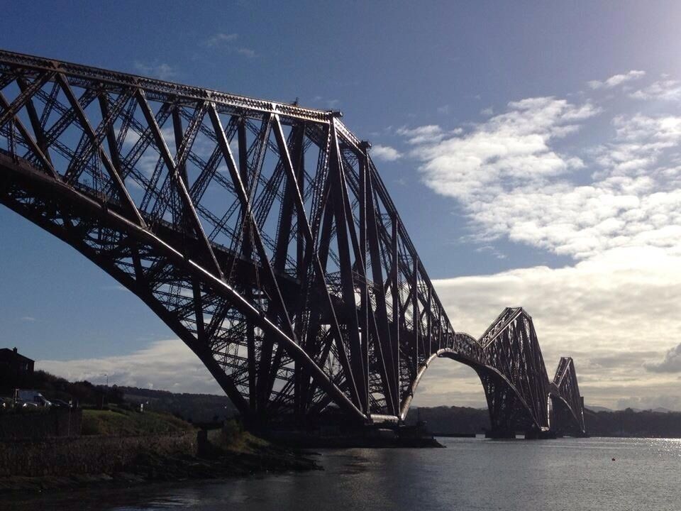 A large steel bridge spanning a river with a clear sky.