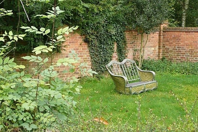 Time for a rest Wicker chair for two in a domestic garden in Yattendon.