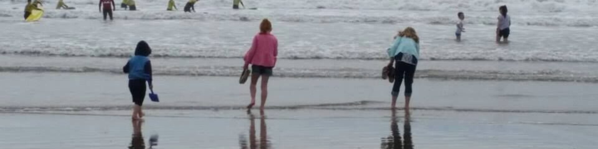 Uma praia com pessoas caminhando e paradas na água.
