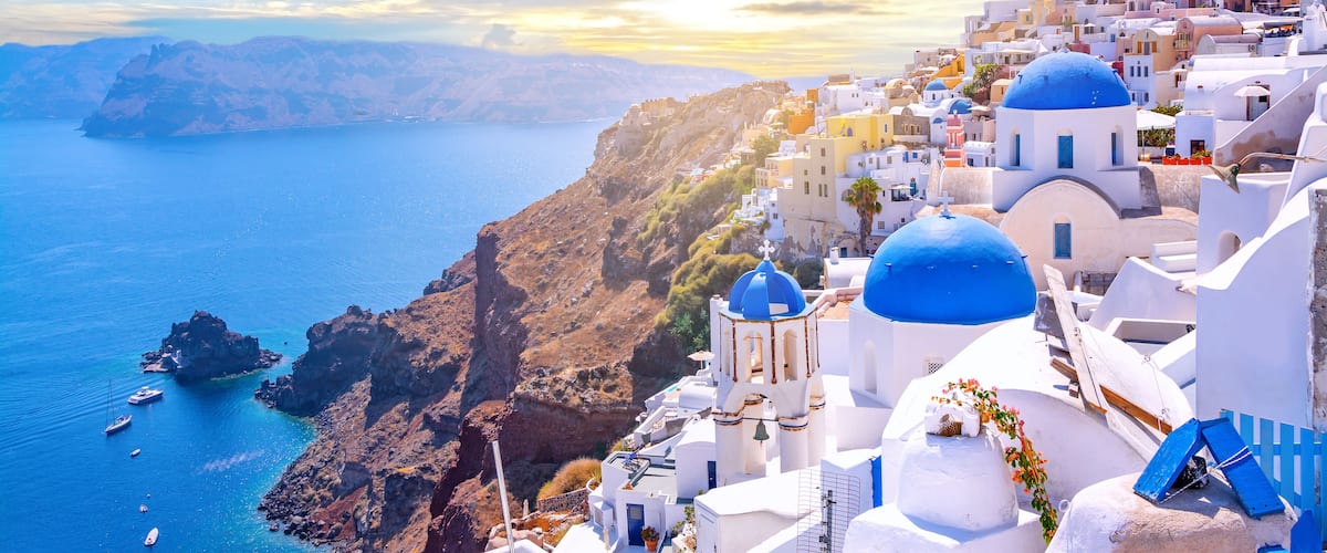 Beautiful Oia town on Santorini island, Greece. Traditional white architecture  and greek orthodox churches with blue domes over the Caldera, Aegean sea. Scenic travel background.