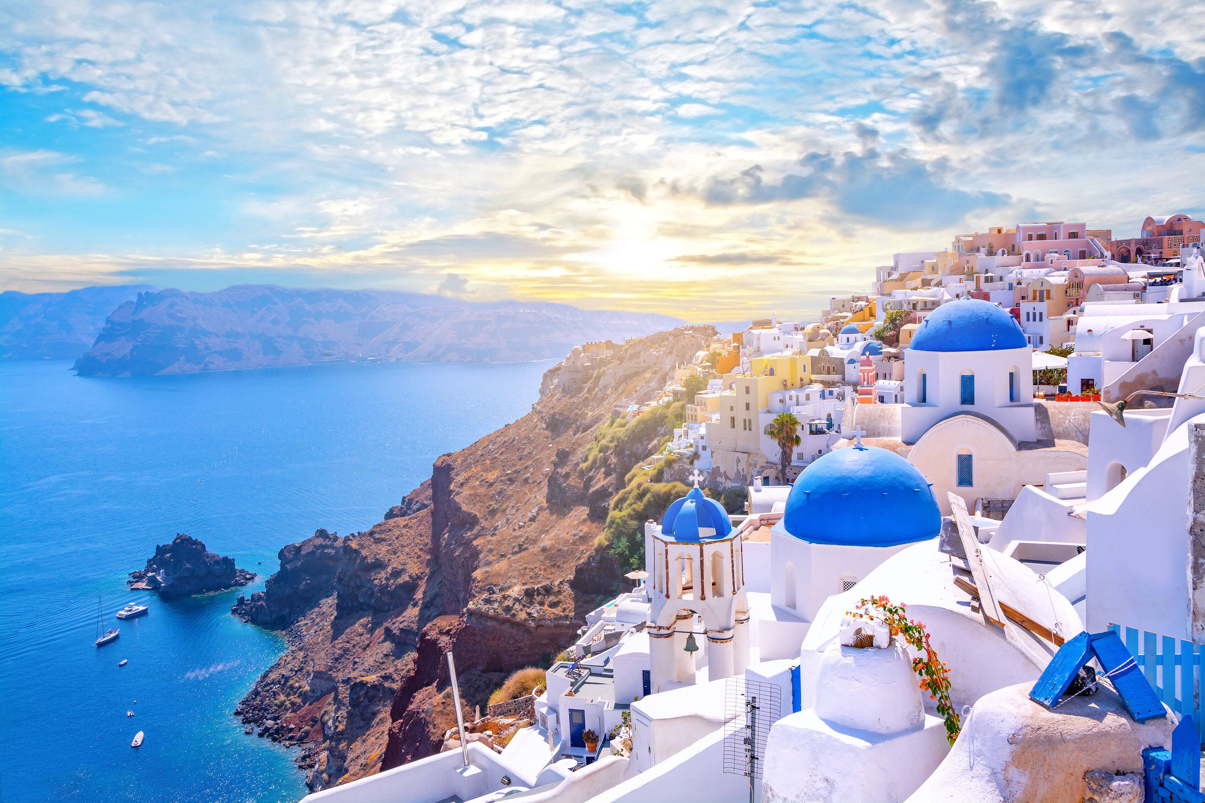 Beautiful Oia town on Santorini island, Greece. Traditional white architecture  and greek orthodox churches with blue domes over the Caldera, Aegean sea. Scenic travel background.