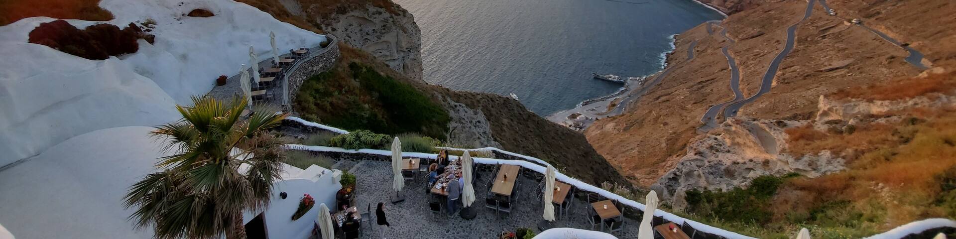 A coastal landscape with a sunset, cliffs, and a restaurant overlooking the sea.