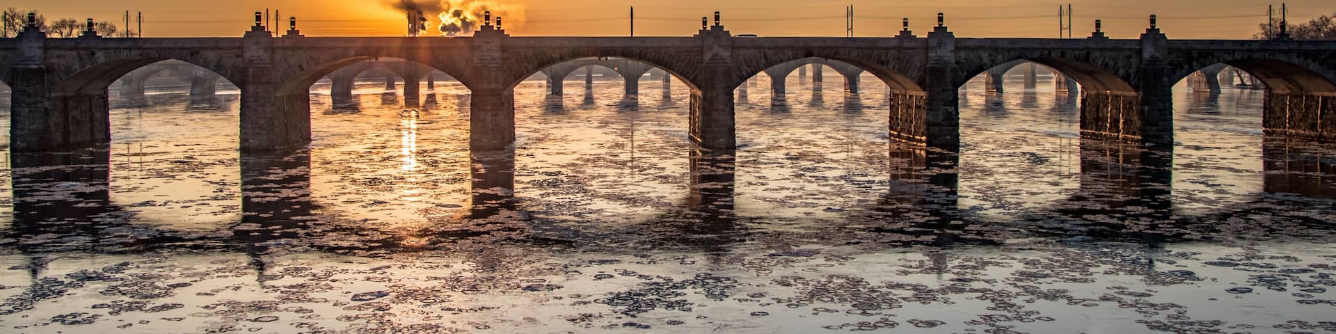 Winter sunrise through the arches of a railroad bridge over an ice-filled Susquehanna River