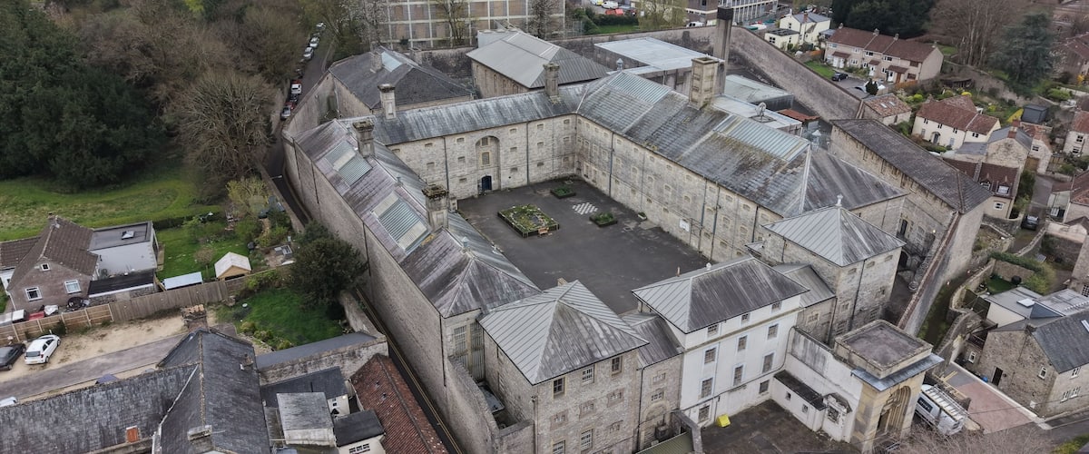 An old stone building with a courtyard surrounded by residential houses.