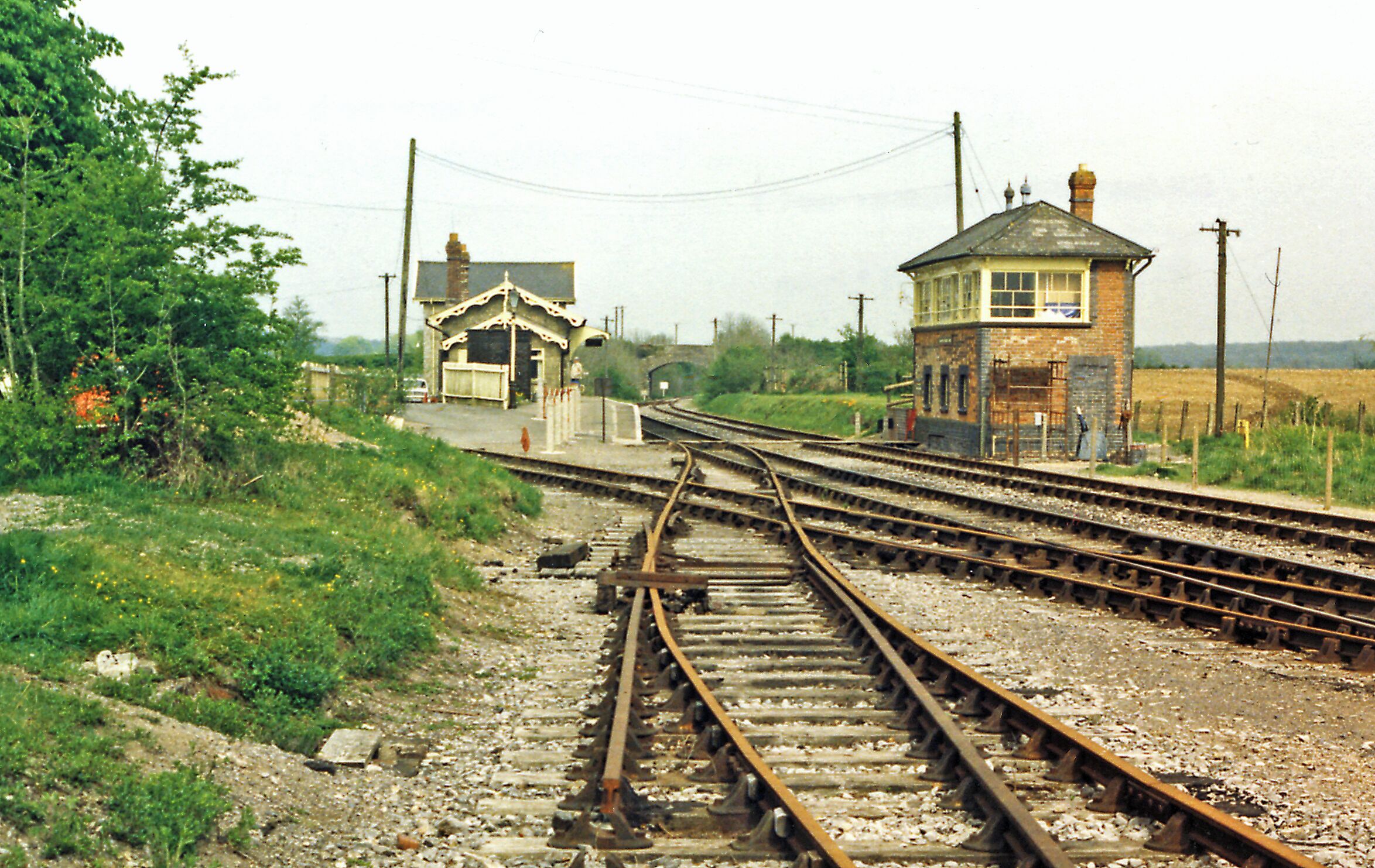 Railway tracks, a small station building, and a signal box in a rural setting.