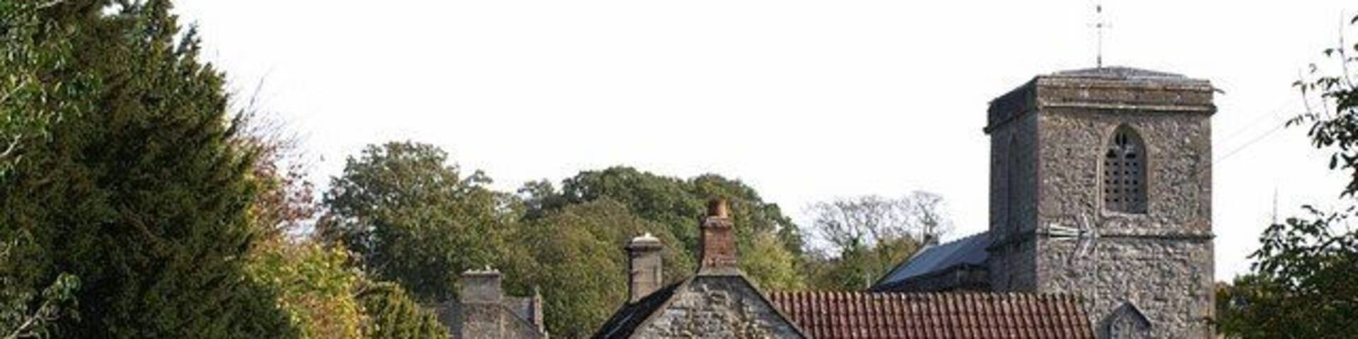Approaching East Pennard church. The footpath from Home Farm approaches a cottage and the west end of the churchyard of 65801.