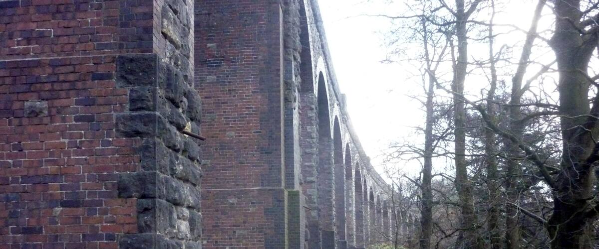 A brick building with a pathway leading through a grassy area with trees.