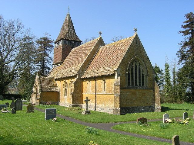 A church with a tall steeple and a graveyard in front.