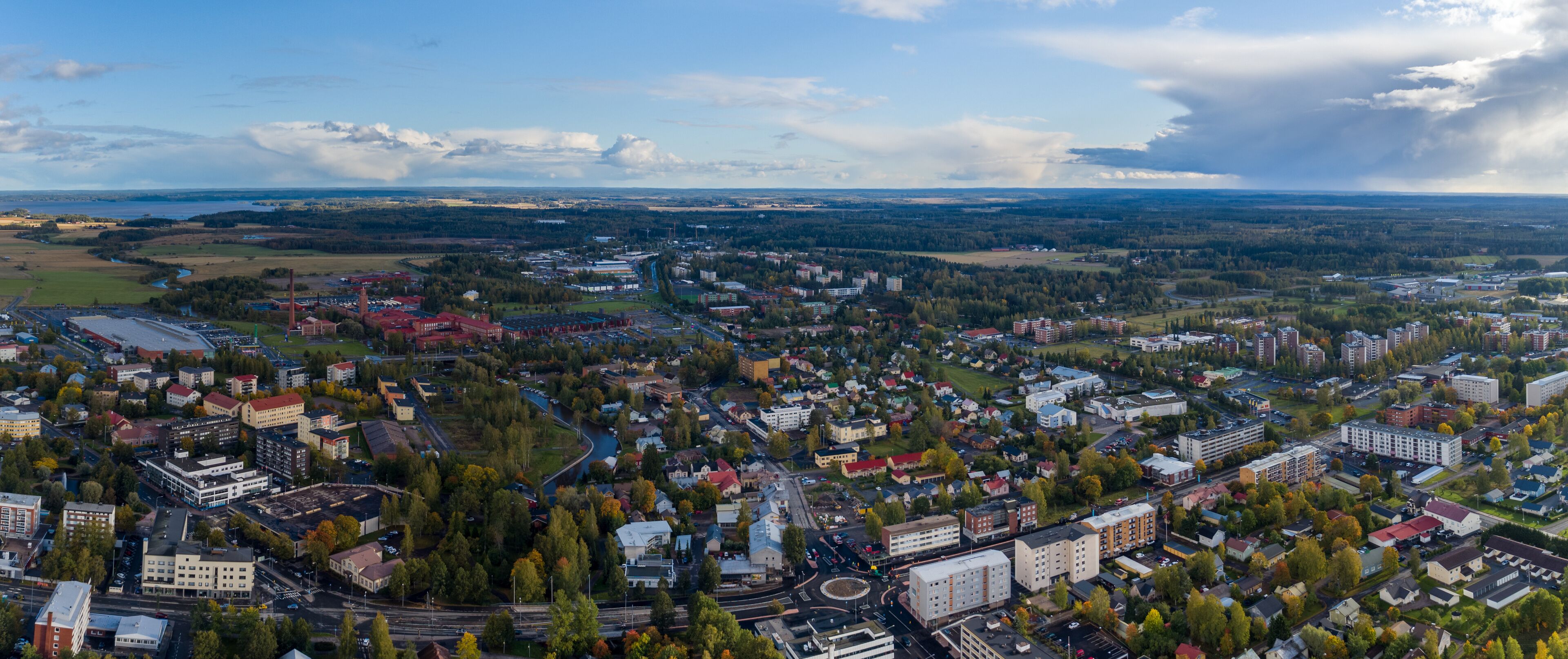An aerial view of a city with a river, buildings, and surrounding greenery.