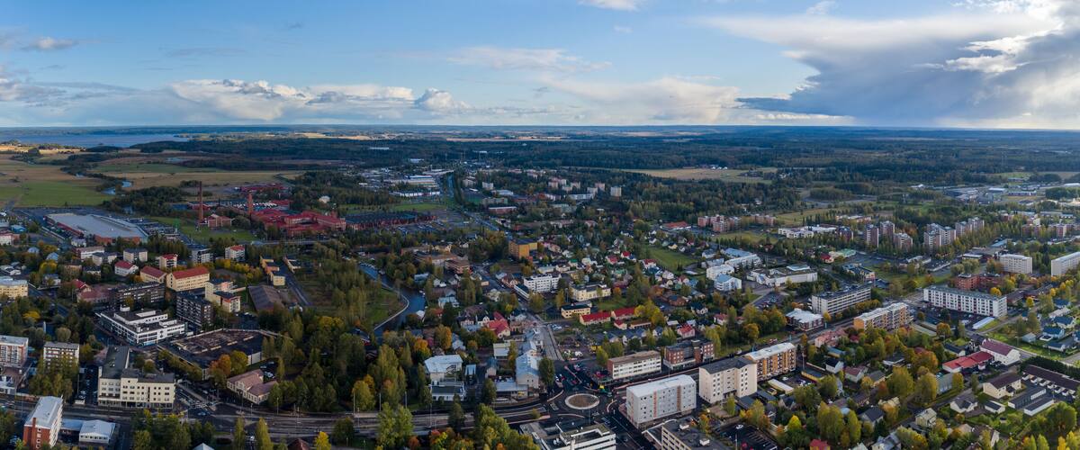 An aerial view of a city with a river, buildings, and surrounding greenery.