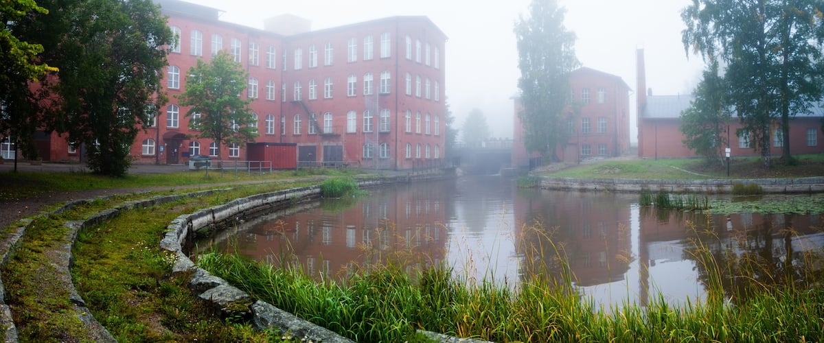 A red brick building with a reflective pond in front.