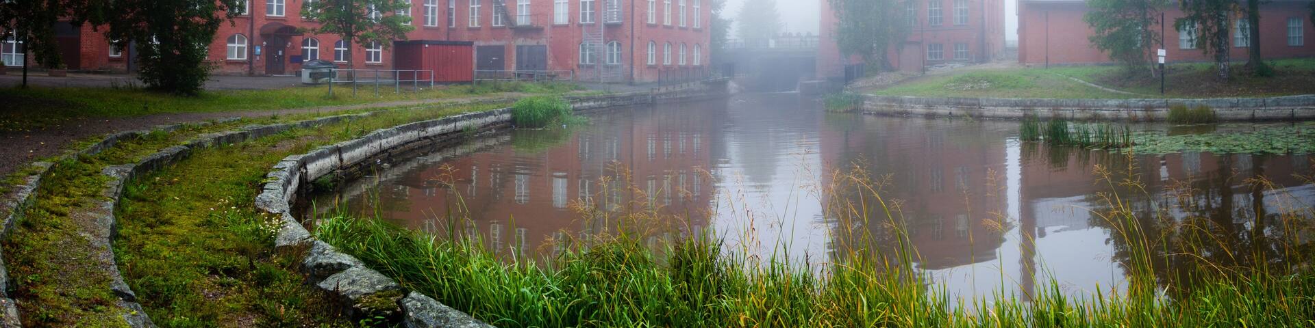 A red brick building with a reflective pond in front.