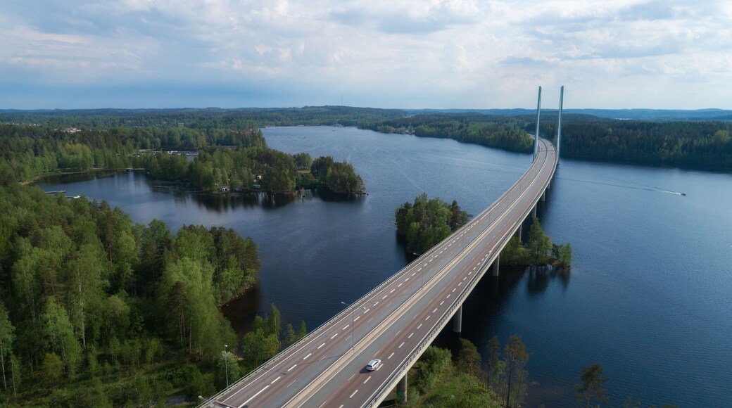 Aerial view of modern bridge across blue lake at summer time. Beautiful sky with clouds. Finland
