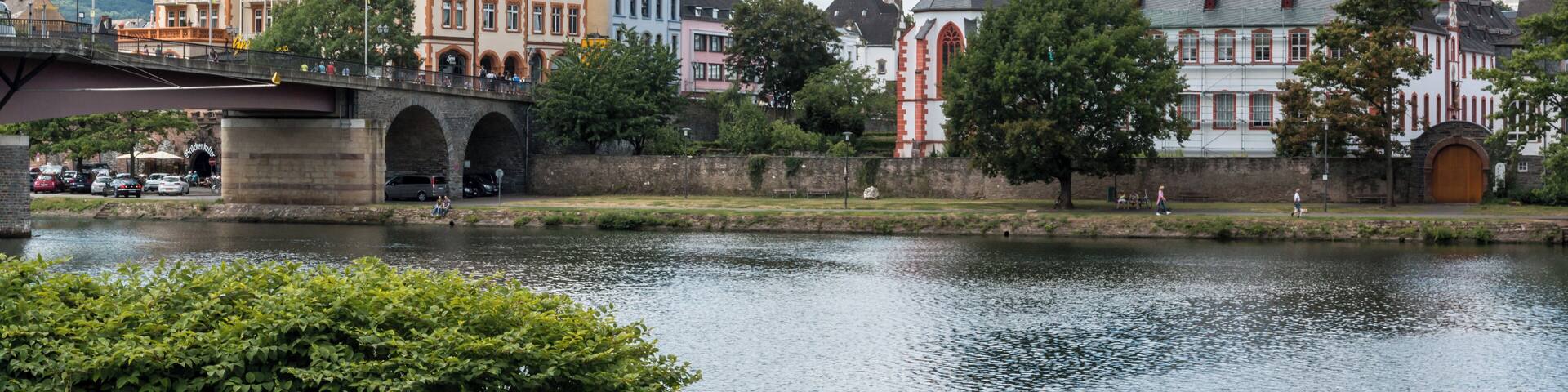 A riverside town with historic buildings, a church, and a bridge.