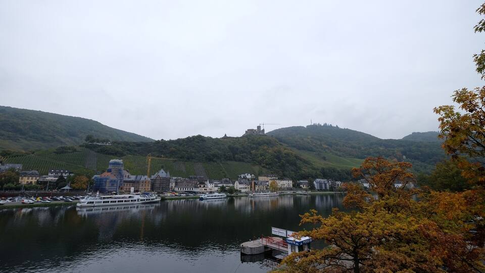 A river with a boat dock, buildings, and hills in the background.