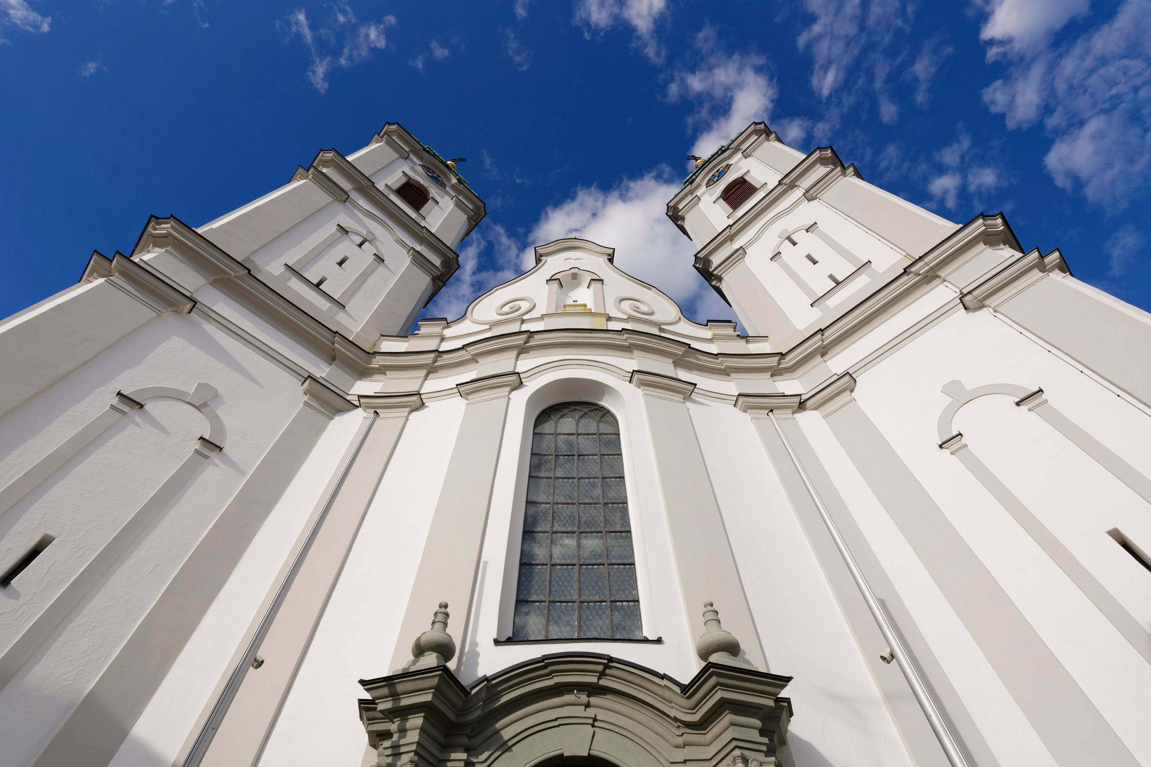 A white church with a large arched window and two bell towers.