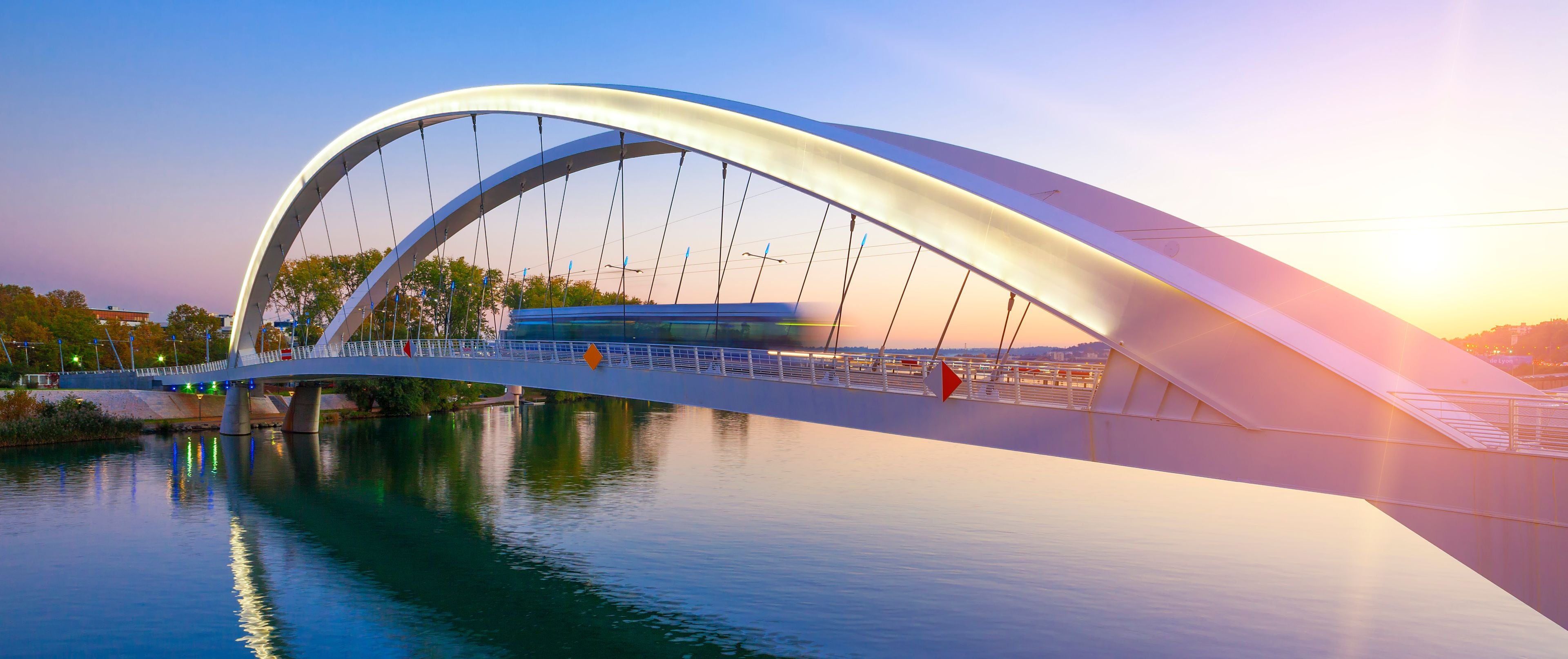 Un pont moderne à la conception incurvée qui enjambe une rivière.