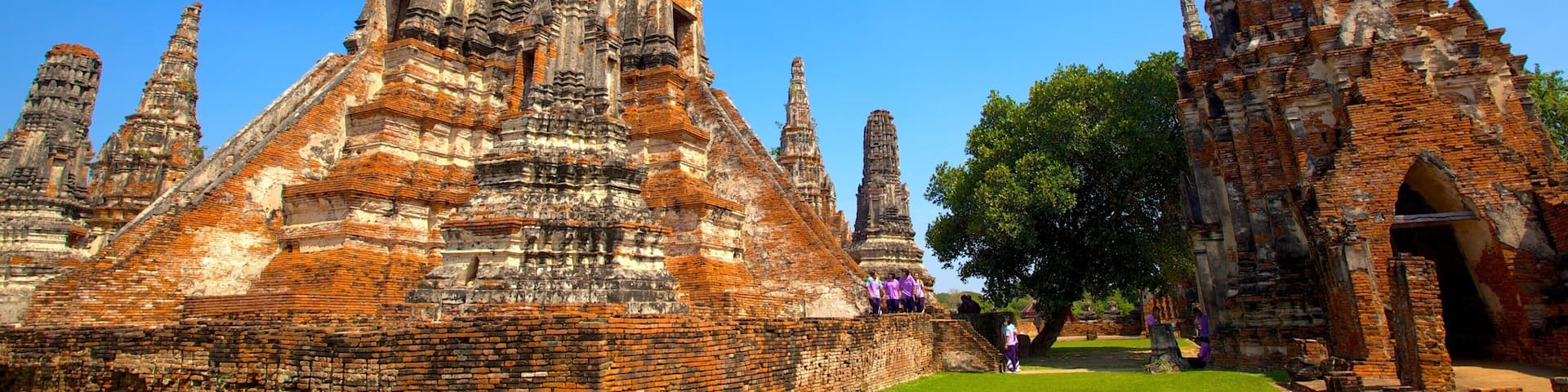 An ancient temple complex with multiple tiered structures and a well-maintained lawn.