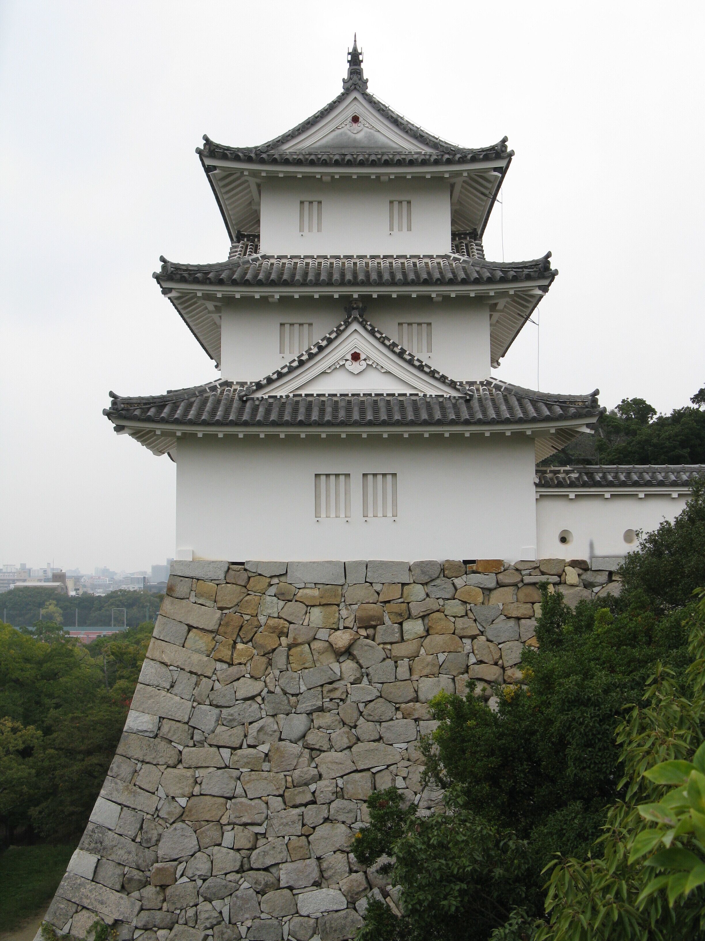 A traditional Japanese castle with a multi-tiered roof and stone walls.