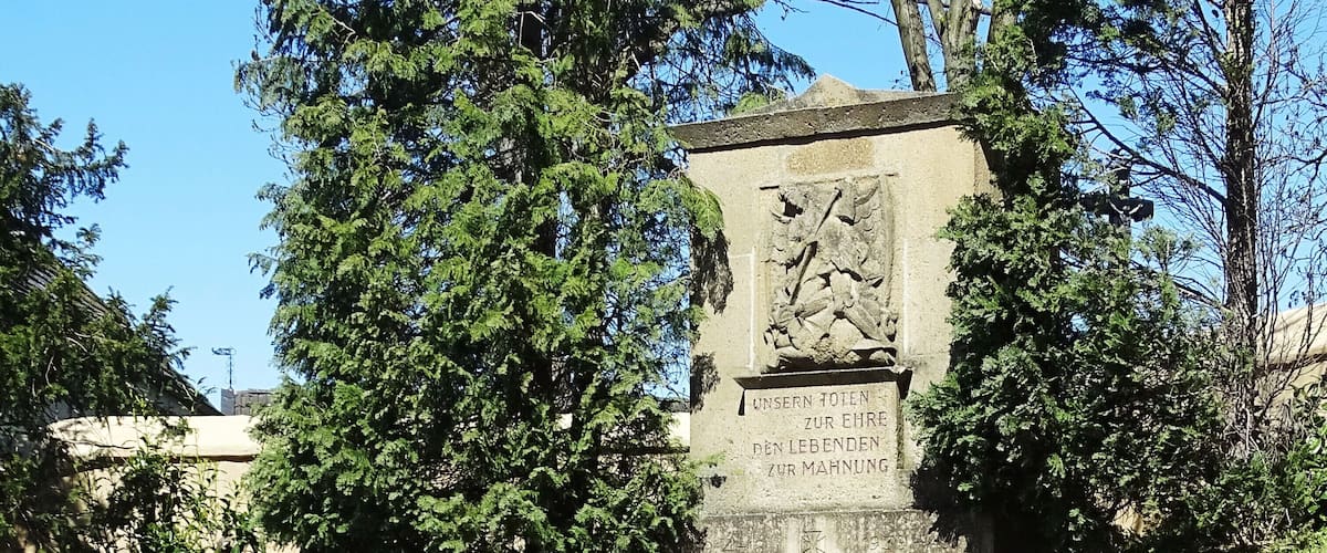 A stone staircase leading up to a monument with inscriptions, surrounded by grass and trees.