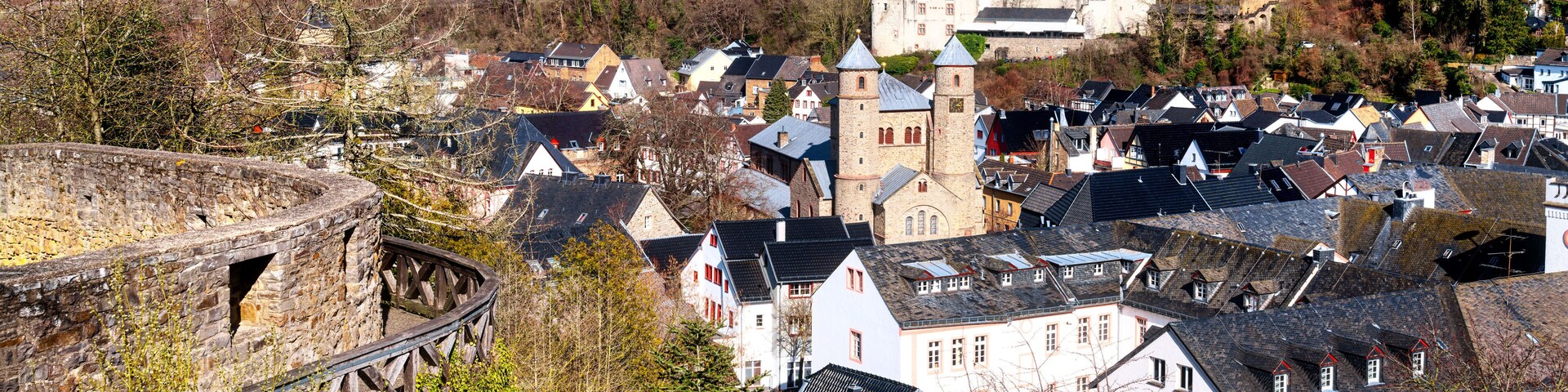 A historic town with a prominent tower, cobblestone streets, and a stone bridge.