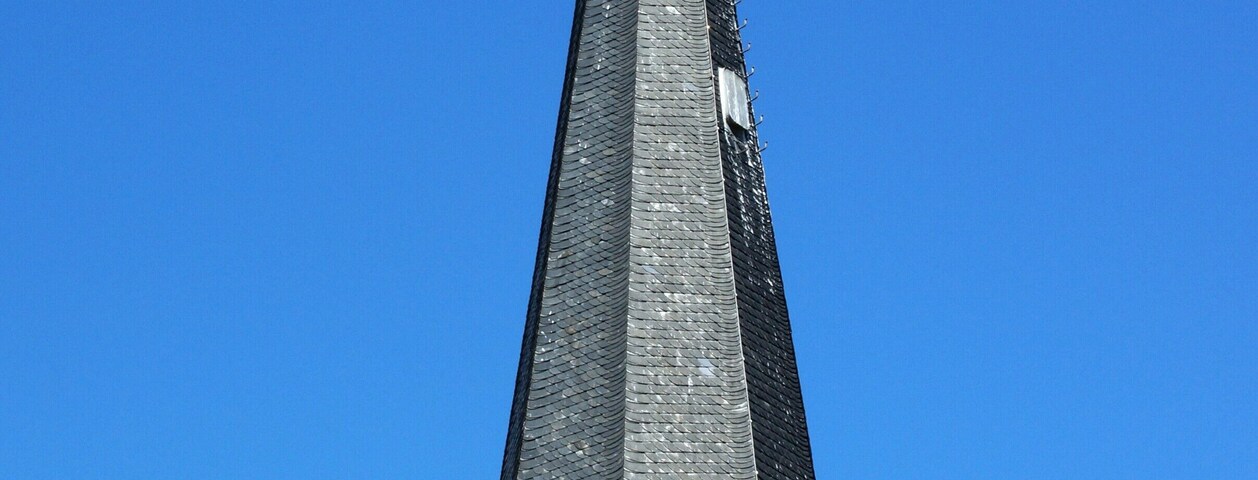 Un campanario de iglesia con veleta y una cruz en la parte superior.