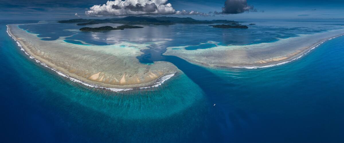 An aerial view of a coral reef with clear blue waters and two prominent coral formations.