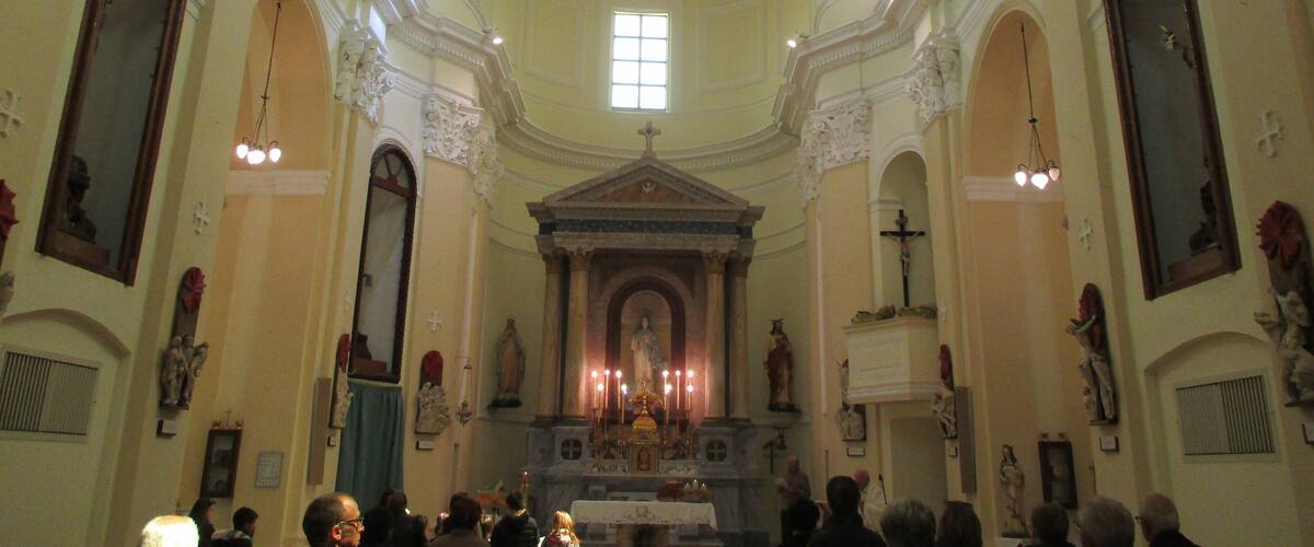 An ornate church interior with a central altar, statues, and a large mural on the ceiling.