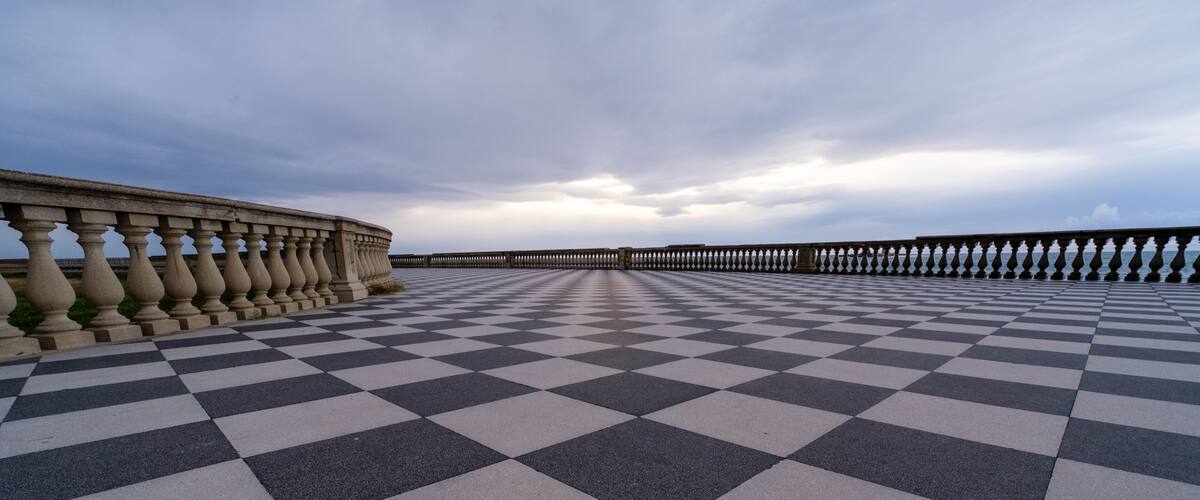 A checkered pavement leading to a wooden pier extending into the water.