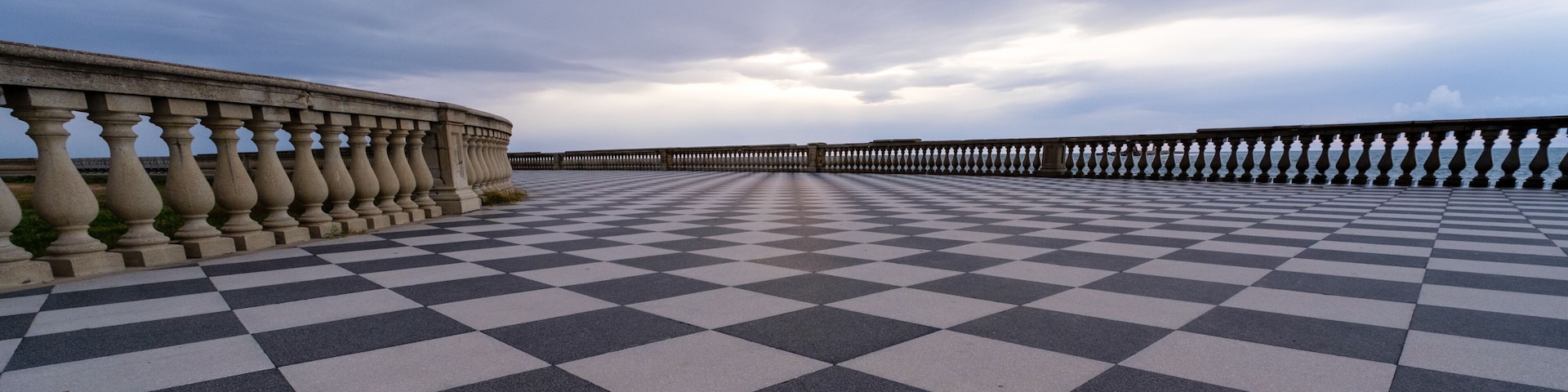 A checkered pavement leading to a wooden pier extending into the water.