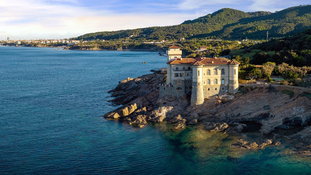 Une ville côtière qui se distingue par un imposant bâtiment ressemblant à un château, situé sur un promontoire rocheux.