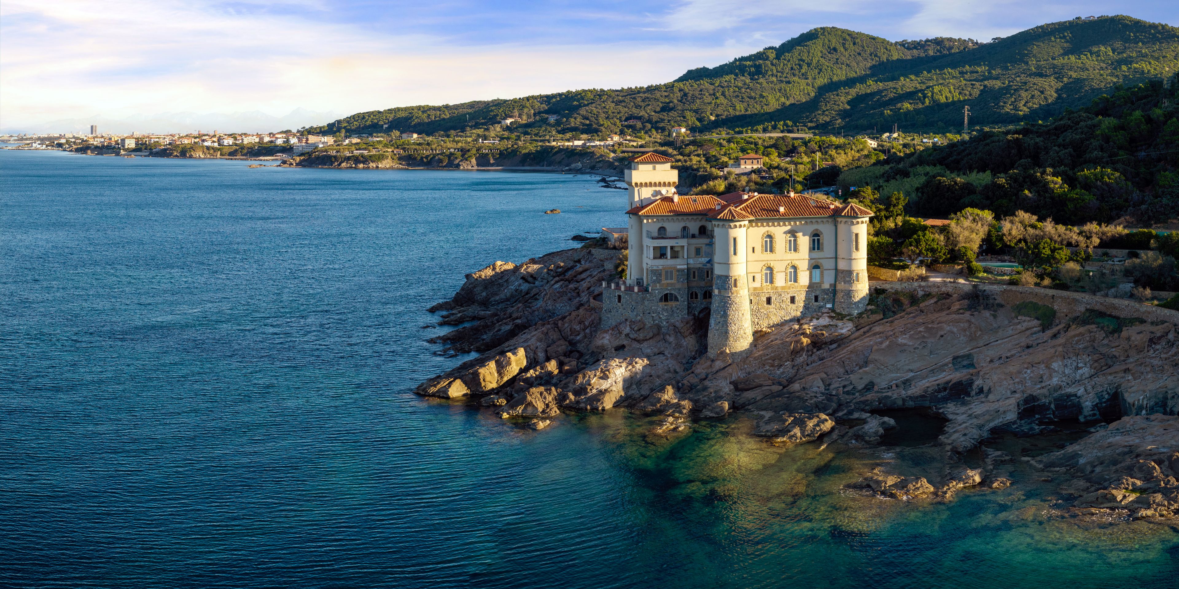 A coastal town with a prominent castle-like building on a rocky outcrop.