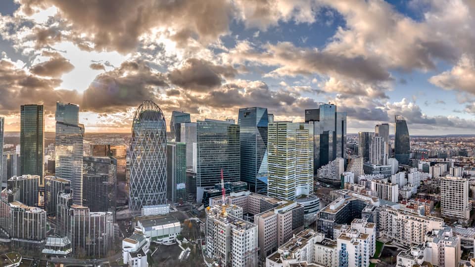 A cityscape with modern skyscrapers and a river in the foreground.