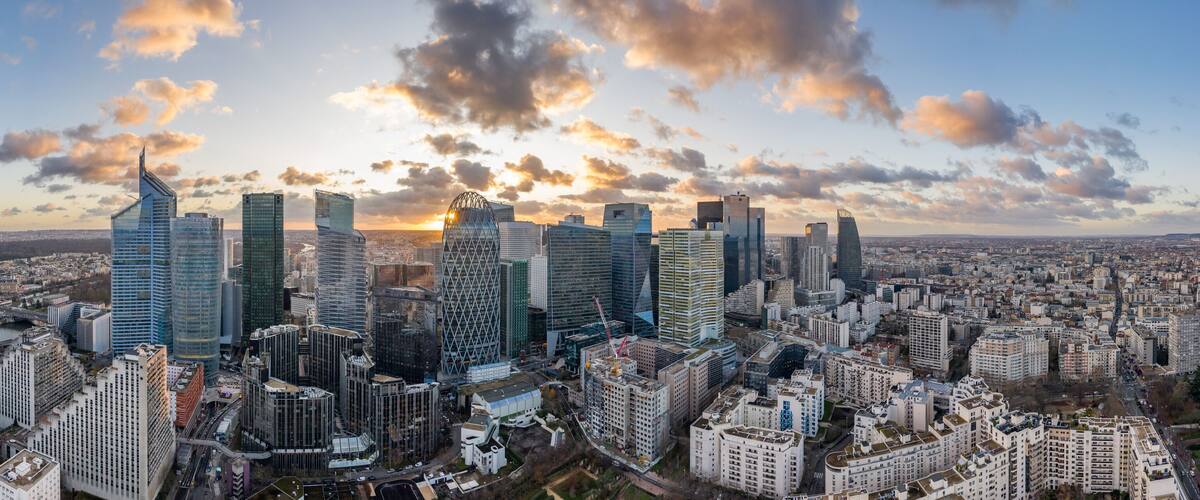 Aerial panoramic drone shot of La Defense skycraper in Paris business district with clouds during sunset