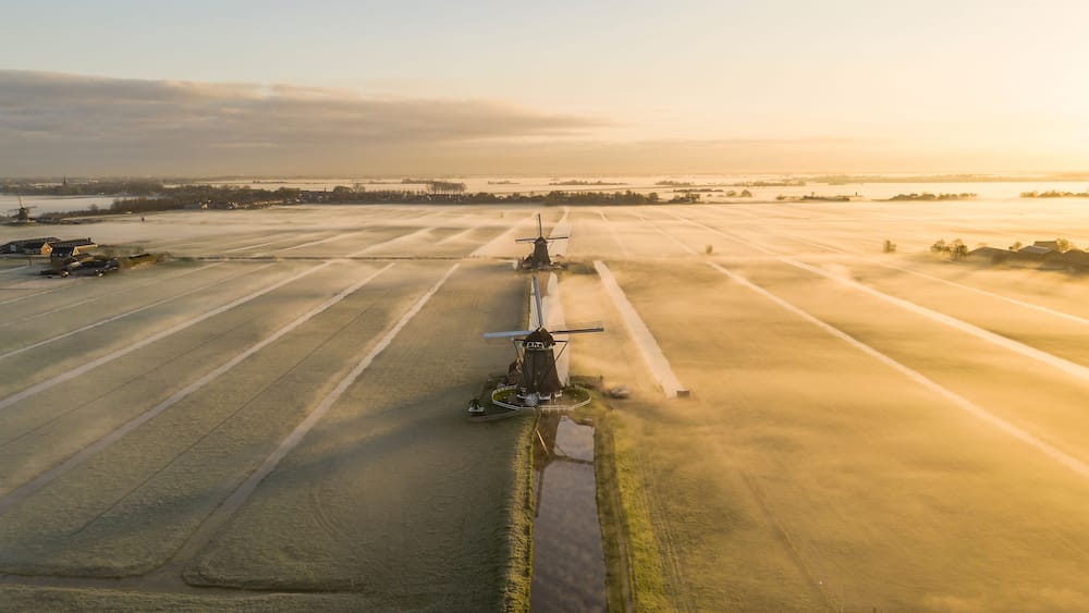Eine Luftaufnahme einer Windmühle in einem Feld mit angrenzendem Ackerland.